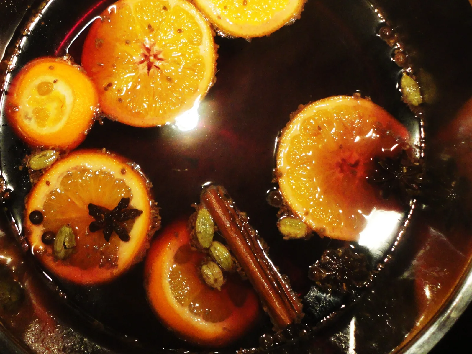 Stovetop pot of simmering water with orange, cinnamon and spices — a homemade simmer pot